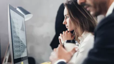 Personas trabajando frente a un monitor con gráficos.