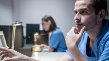 Hombre en uniforme médico mirando una pantalla con atención.