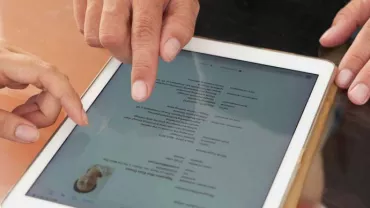 Dos personas usando una tableta para revisar un documento.
