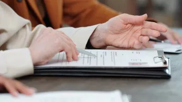 Manos revisando documentos en una mesa de madera.