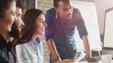 Grupo de personas trabajando juntas frente a una computadora.