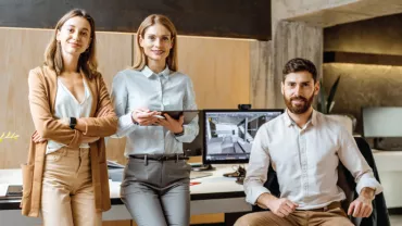 Tres personas en una oficina moderna con computadoras.