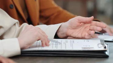 Manos revisando documentos en una mesa.