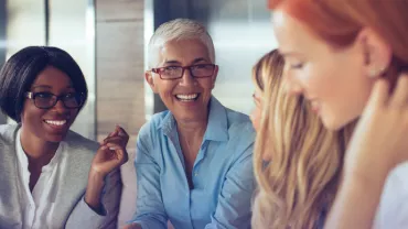 Grupo de personas sonriendo y conversando en una oficina.