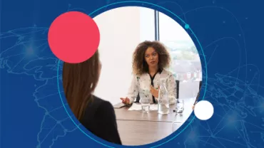 Mujer hablando en una reunión con fondo azul y círculos.