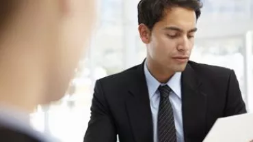 Hombre en traje leyendo un documento en una oficina.