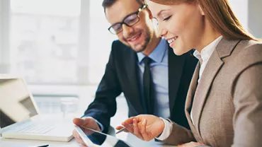 Dos personas revisando información en una tablet en una oficina.