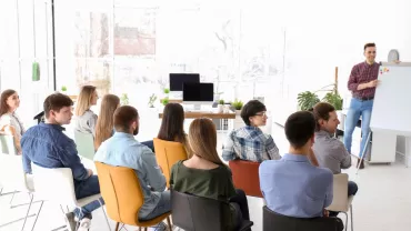 Grupo de personas en una sala de conferencias escuchando una presentación.