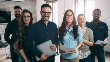 Grupo de personas sonrientes con documentos en oficina.