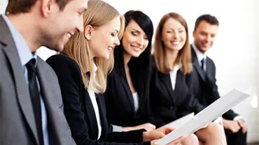 Grupo de personas en trajes formales revisando documentos.