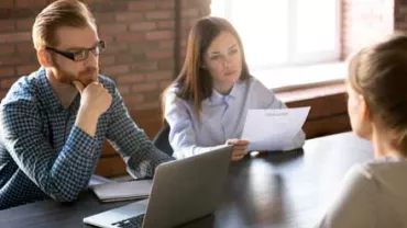 Entrevista de trabajo con dos entrevistadores y una candidata.