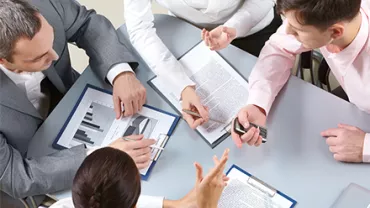 Reunión de trabajo con documentos y gráficos en una mesa.