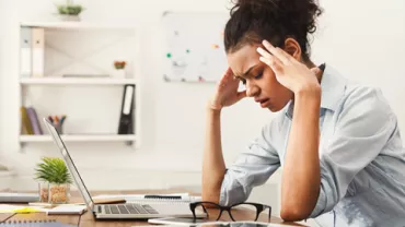 Mujer estresada frente a una computadora en la oficina.