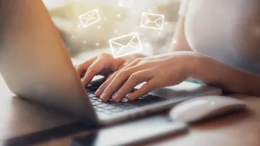 Persona escribiendo en un portátil con iconos de correo.