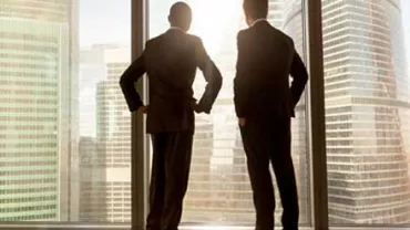 Dos hombres de negocios mirando una ciudad desde una ventana.