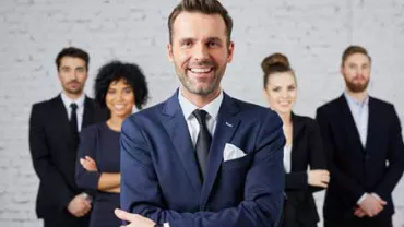 Hombre de negocios sonriente en el centro con colegas al fondo.