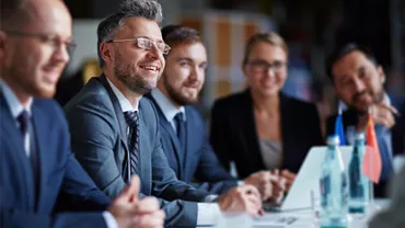 Grupo de personas en una reunión de negocios, sonriendo y conversando.