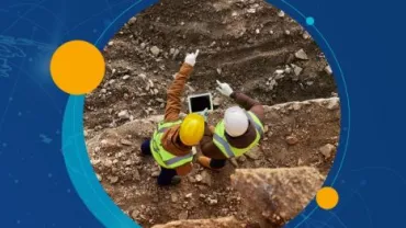 Dos trabajadores de la construcción revisan una tablet en un sitio de excavación.