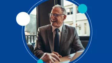 Hombre mayor sonriente con traje y corbata en oficina.