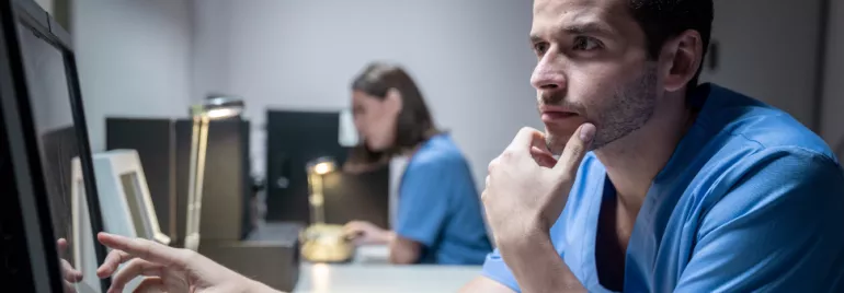 Hombre en uniforme médico mirando una pantalla con atención.