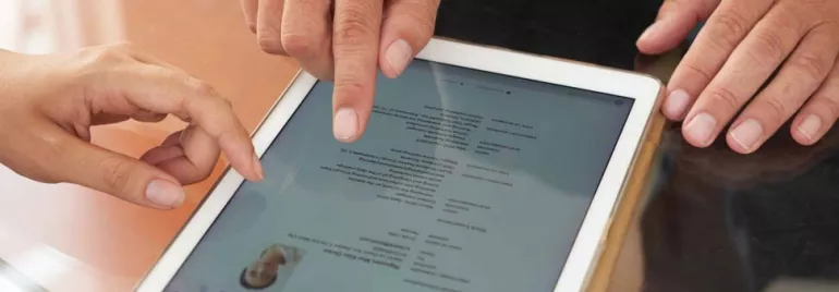Dos personas usando una tableta para revisar un documento.