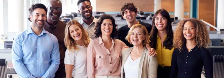 Grupo diverso de personas sonriendo en una oficina.