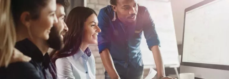 Grupo de personas trabajando juntas frente a una computadora.
