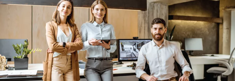 Tres personas en una oficina moderna con computadoras.