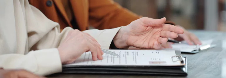Manos revisando documentos en una mesa.