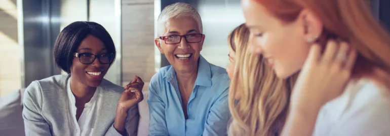 Grupo de personas sonriendo y conversando en una oficina.