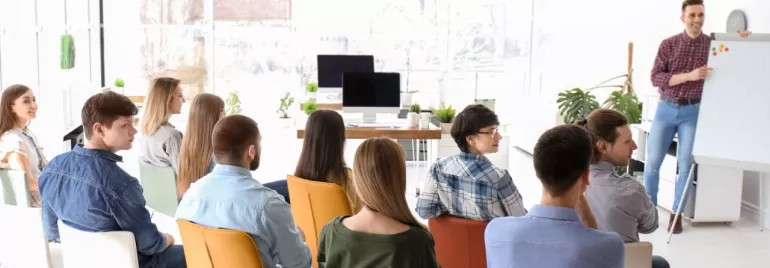 Grupo de personas en una sala de conferencias escuchando una presentación.