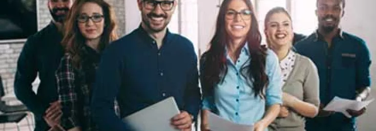 Grupo de personas sonrientes con documentos en oficina.