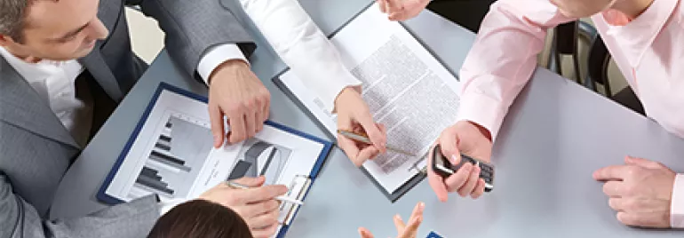 Reunión de trabajo con documentos y gráficos en una mesa.