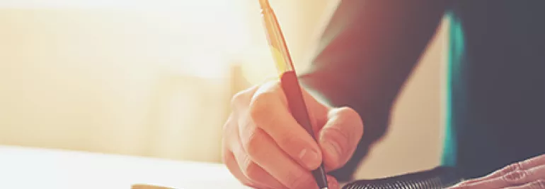 Persona escribiendo en un cuaderno con buena iluminación.