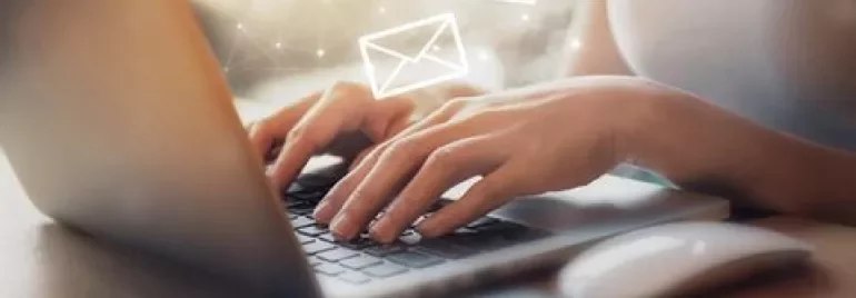 Persona escribiendo en un portátil con iconos de correo.