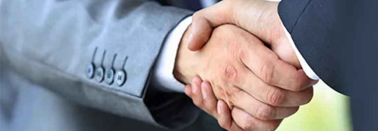 Dos personas dándose la mano en señal de acuerdo.