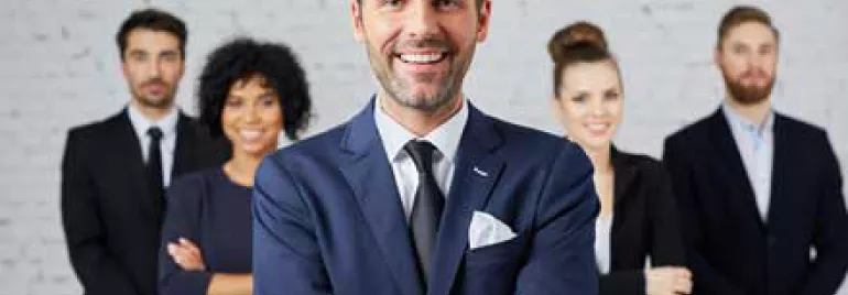 Hombre de negocios sonriente en el centro con colegas al fondo.