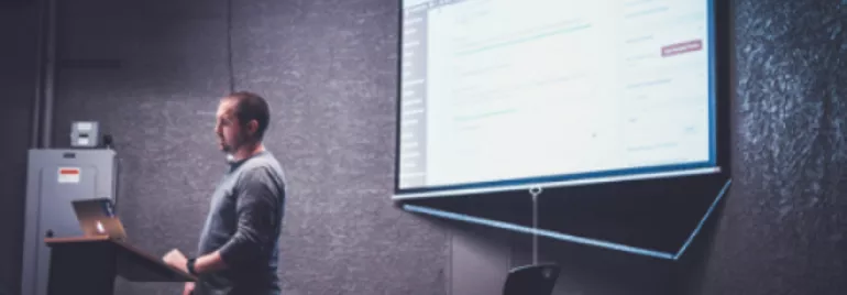 Hombre presentando en una pantalla grande con proyector.