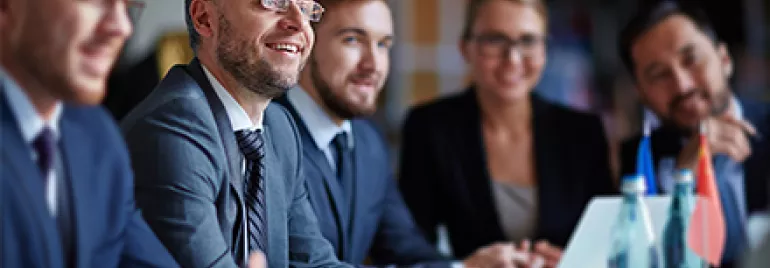Grupo de personas en una reunión de negocios, sonriendo y conversando.