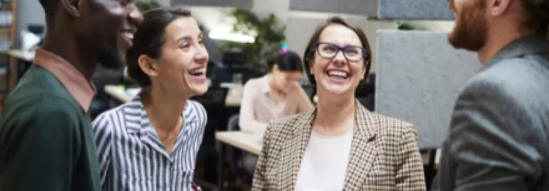 Personas conversando y riendo en una oficina.