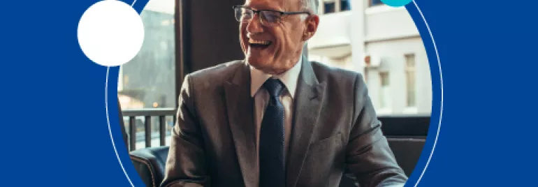 Hombre mayor sonriente con traje y corbata en oficina.
