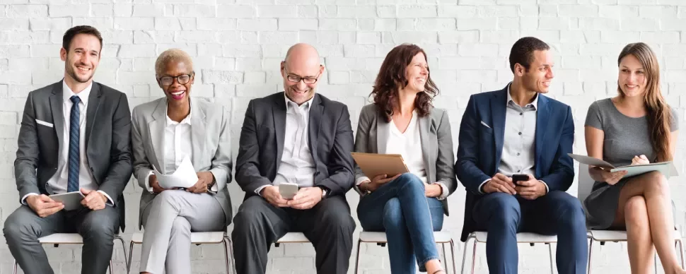 Varias personas sentadas sonriendo en una fila.