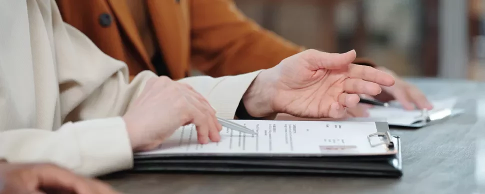 Manos revisando documentos en una mesa.