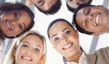 Grupo de personas sonriendo, mirando hacia abajo.