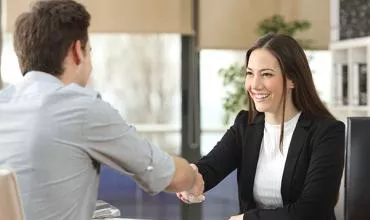 Dos personas estrechando manos en una reunión de oficina.