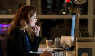 Mujer trabajando en la computadora de noche en una oficina.