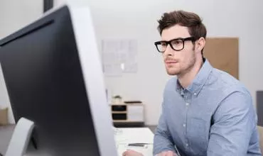 Hombre con gafas trabajando en una computadora de escritorio.