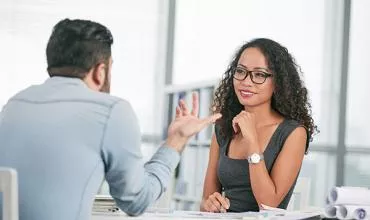 Mujer y hombre en reunión de negocios, dialogando en una oficina.