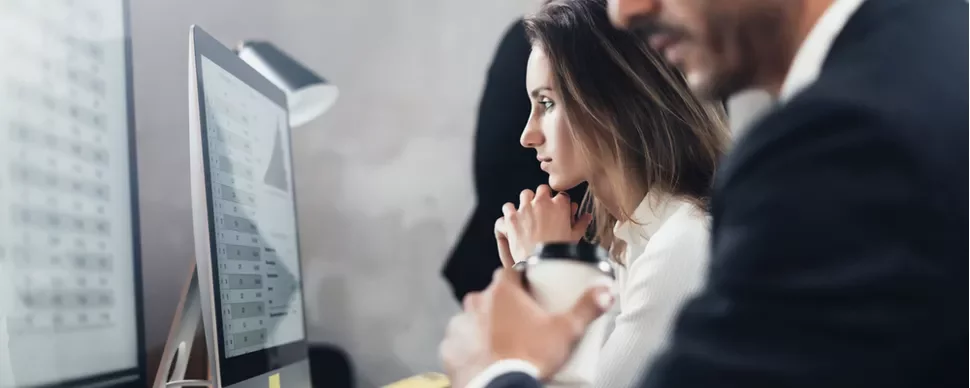 Personas trabajando frente a un monitor con gráficos.
