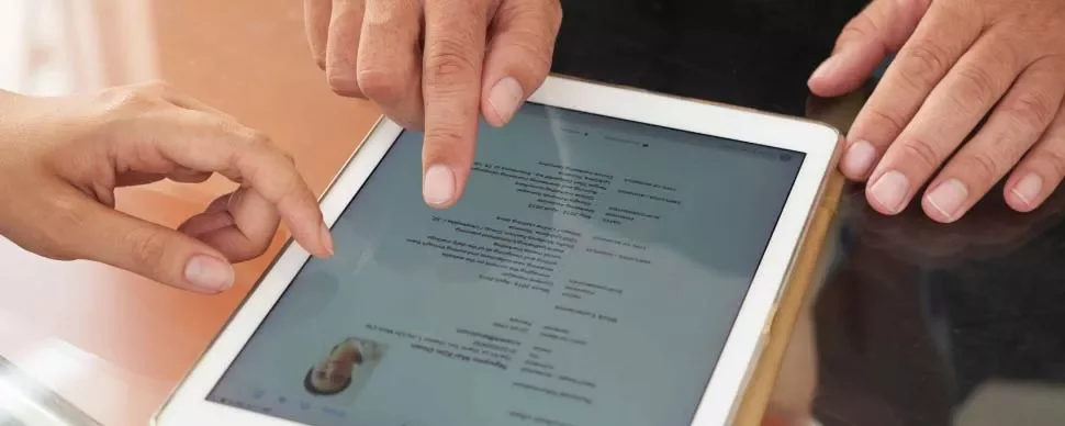Dos personas usando una tableta para revisar un documento.